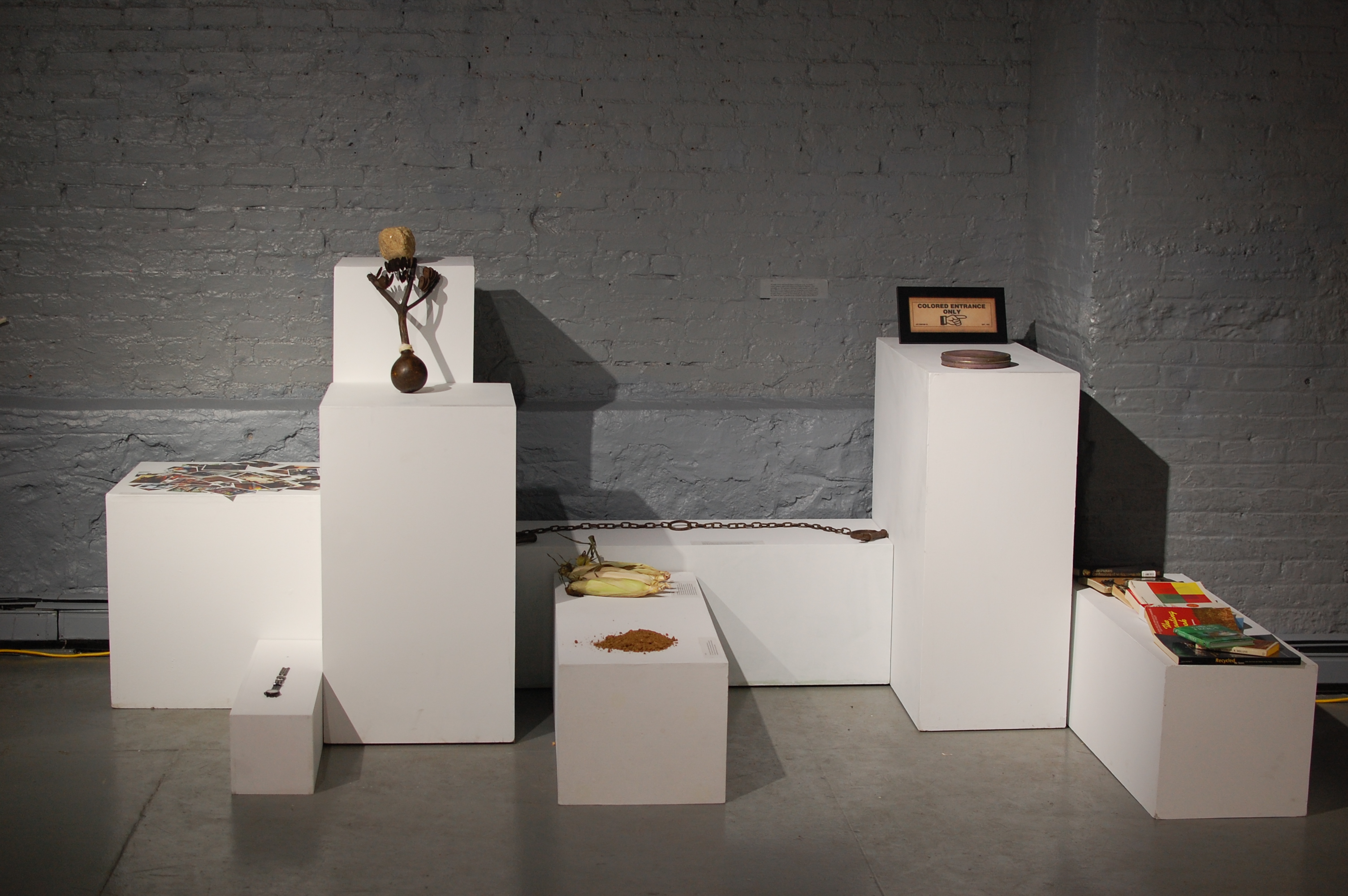 jasmine_murrell-15_Perceived_Obsolescence_2015_site-specific_dirt_air_ears_of_corn_slave_shackles_sign_postcards_books_rock_and_a_musical_instrument