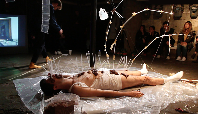 Now You [Play Dead] (Love Letter to a Satellite), 2017 Performance - Brother, Sister, Tubing, straws, string, grid, containers of water, clay, bandages, 3 hours, spoken words and choreography by Mark Bleakley, sound improvised by Nikhil Shah [performance still]